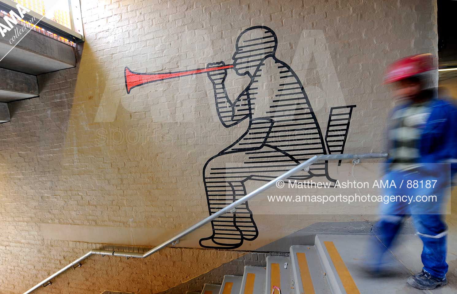 A construction workman walks past a mural of a South African football fan blowing a horn, indicating to fans the direction to their seats during the construction of Soccer City Stadium in Johannesburg, South Africa.