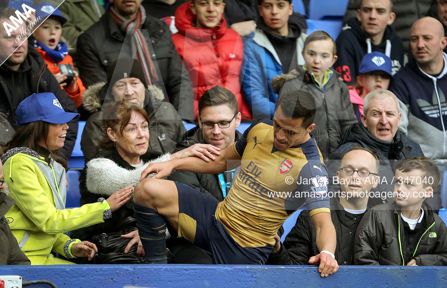 19 March 2016 Barclays Premier League - Everton v Arsenal - Alexis Sanchez of Arsenal is helped up by Everton supporters after he fell over the advertising boards © James Baylis / AMA 347040